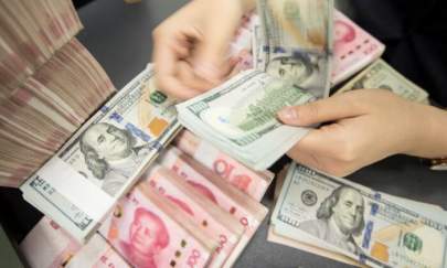 A Chinese bank employee counts 100-yuan notes and U.S. dollar bills at a bank counter in Nantong in eastern China's Jiangsu Province on Aug. 6, 2019. (STR/AFP via Getty Images)