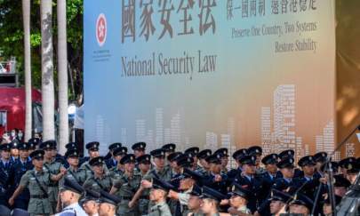 Attendees from various forces march next to a banner supporting the new national security law at the end of a flag-raising ceremony to mark the 23rd anniversary of Hong Kong's handover from Britain in Hong Kong on July 1, 2020. (Anthony Wallace/AFP via Getty Images)