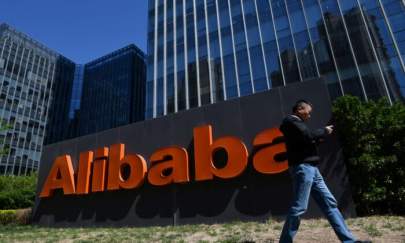 A man walks past an Alibaba sign outside the company's office in Beijing on April 13, 2021. (Greg Baker/AFP via Getty Images)