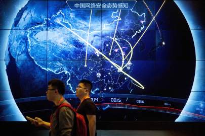 In this 2017 file photo, attendees walk past an electronic display showing recent cyberattacks in China at the China Internet Security Conference in Beijing. Tech experts in China who find a weakness in computer security would be required to tell the government instead of publicizing it under rules announced July 13, 2021, as part of the ruling Communist Party’s sweeping effort to tighten control over information. (Mark Schiefelbein/AP) (AP)