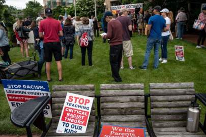 Signs are seen on a bench during a rally against "critical race theory" (CRT) being taught in schools in Leesburg, Virginia, on June 12.(ANDREW CABALLERO-REYNOLDS/AFP VIA GETTY IMAGES)