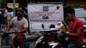 AP - Motorists wait next to a banner that says only those vehicles with QR codes will be given fuel at a fuel station in Colombo, Sri Lanka, Aug. 1, 2022.