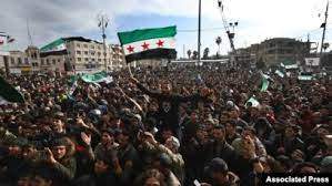 FILE - Associated Press - Thousands of anti-Syrian government protesters shout slogans and wave revolutionary flags to mark 10 years since the start of a popular uprising against President Bashar Assad's rule, March 15, 2021.