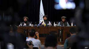 AP - FILE - In front of a Taliban flag, Taliban spokesman Zabihullah Mujahid, center, speaks at his first news conference, in Kabul, Afghanistan, Aug. 17, 2021